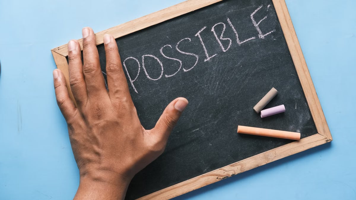 A hand on a chalkboard with 'Possible' written in chalk signifies optimism and potential.